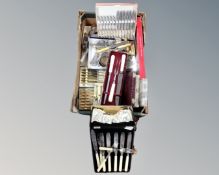 A box containing a large quantity of boxed and loose flatware.