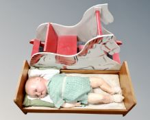 A child's doll in cot together with a rocking seat.
