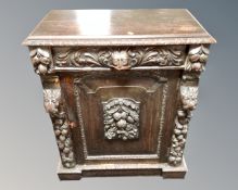 A Victorian heavily carved oak single door cabinet fitted with a drawer.