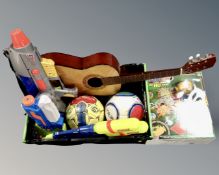 A crate containing toys, footballs, acoustic guitar.