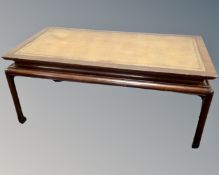 A mahogany Chinese style coffee table with leather inset panel