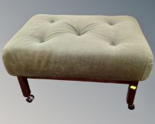 A late 20th century footstool on castors upholstered in a green buttoned dralon.