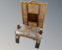 An antique camel stool with leather saddle together with a brass inlaid hardwood panel fire screen,