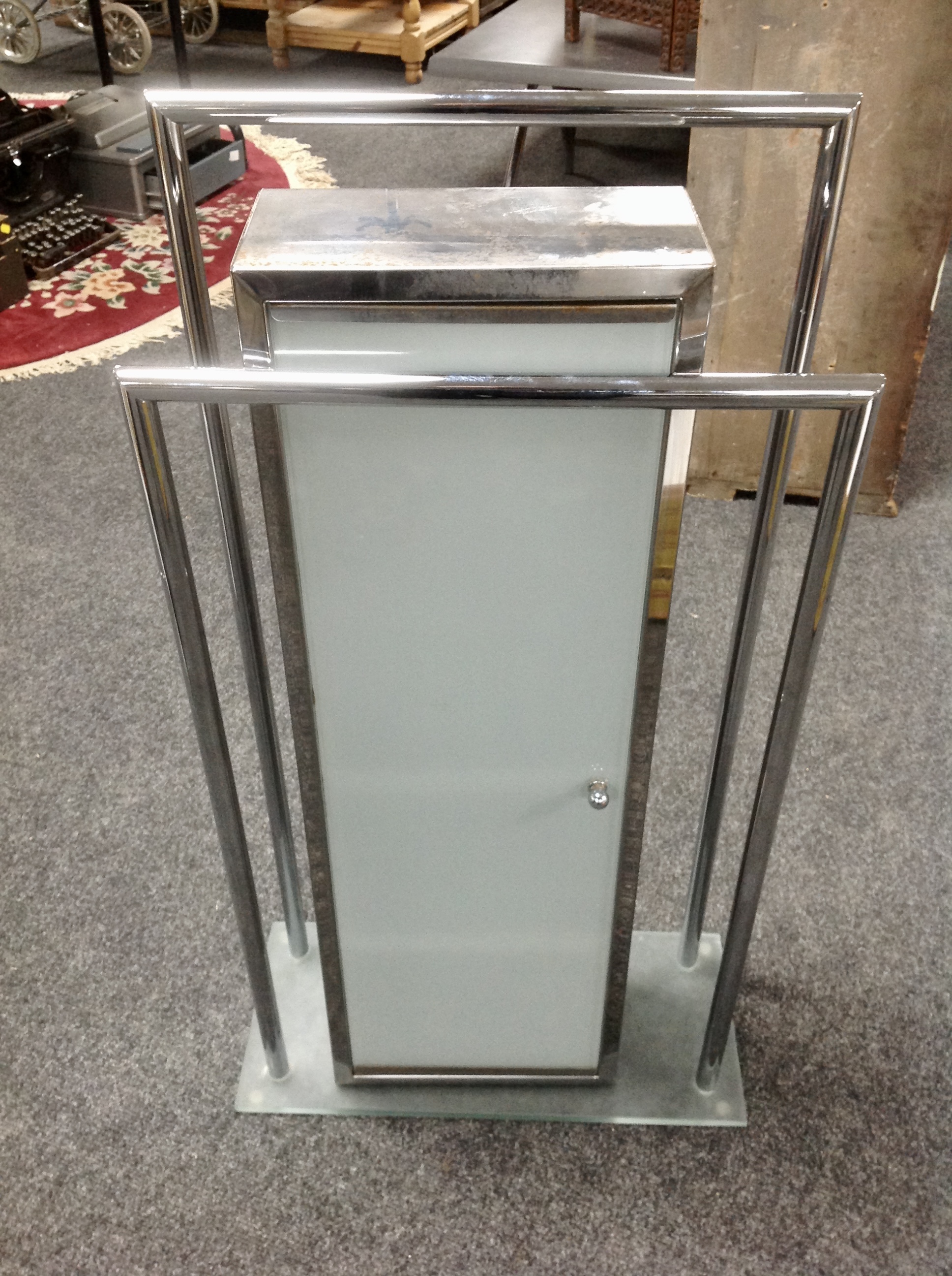 A contemporary bathroom cabinet with frosted door together with a towel rail.