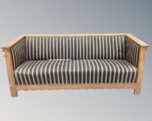 An early 20th century oak framed hall settee in striped fabric