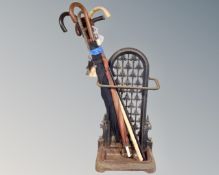 A Victorian style cast iron stick stand together with a quantity of walking sticks and parasols.