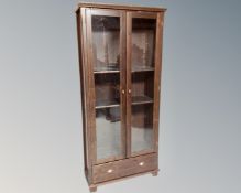 A stained pine glazed double door bookcase fitted with a drawer beneath.