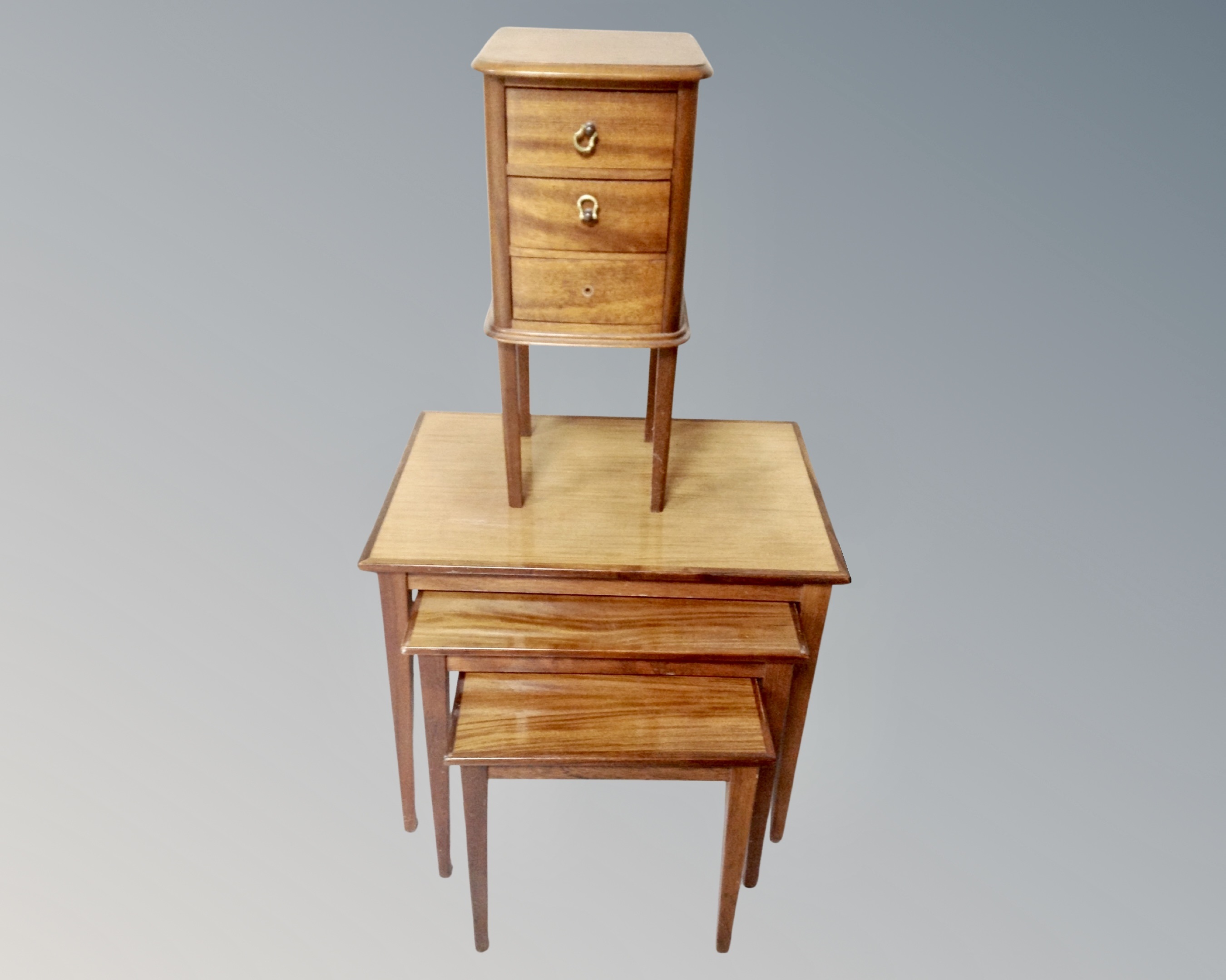 A nest of three Danish mid-century tables together with a narrow mahogany three drawer chest on