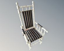 A white painted rocking chair in striped upholstery.