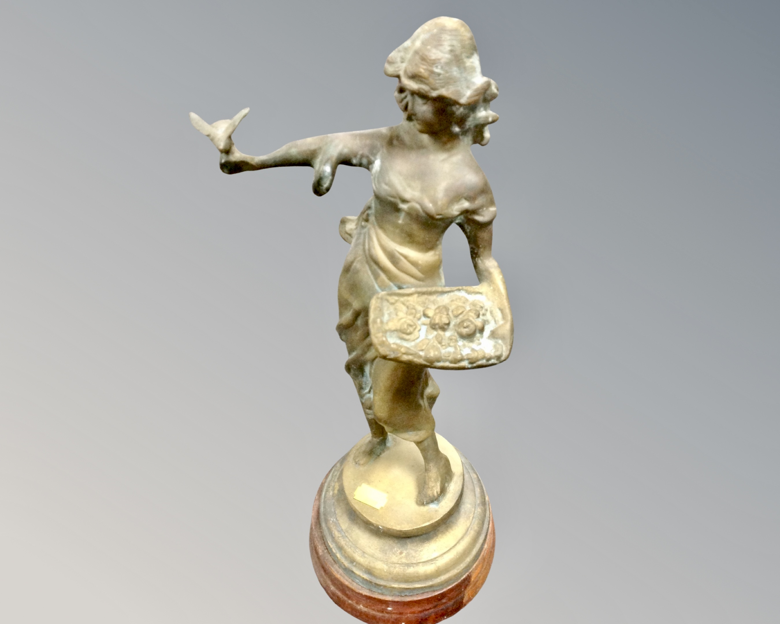A bronze figure on socle base depicting a lady holding a dove.