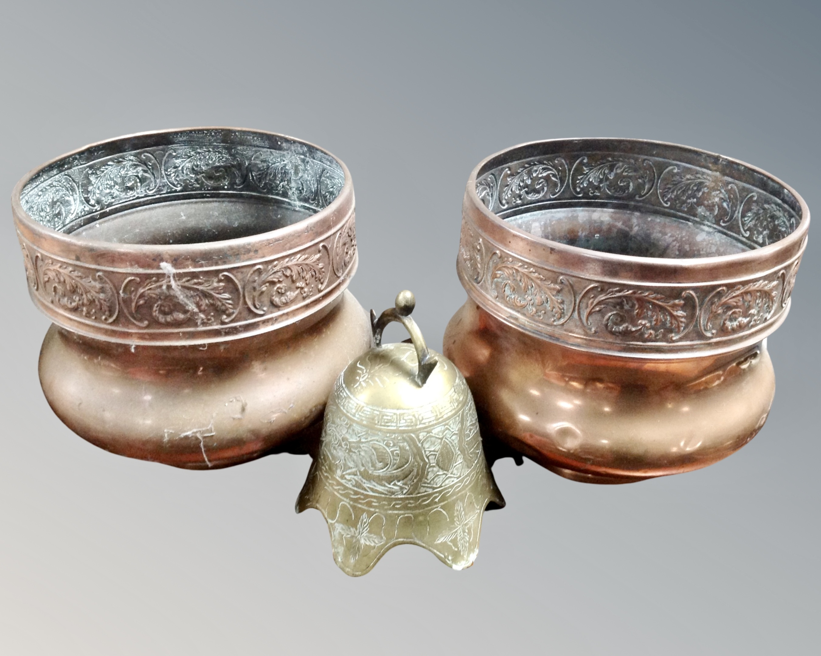 A pair of vintage embossed copper planters together with a brass embossed Oriental style bell.