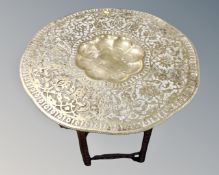 An impressive Indian embossed brass topped occasional table on a heavily carved base.