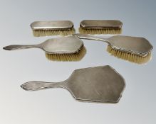 A silver five-piece dressing table set comprising hand mirror and two pairs of brushes,