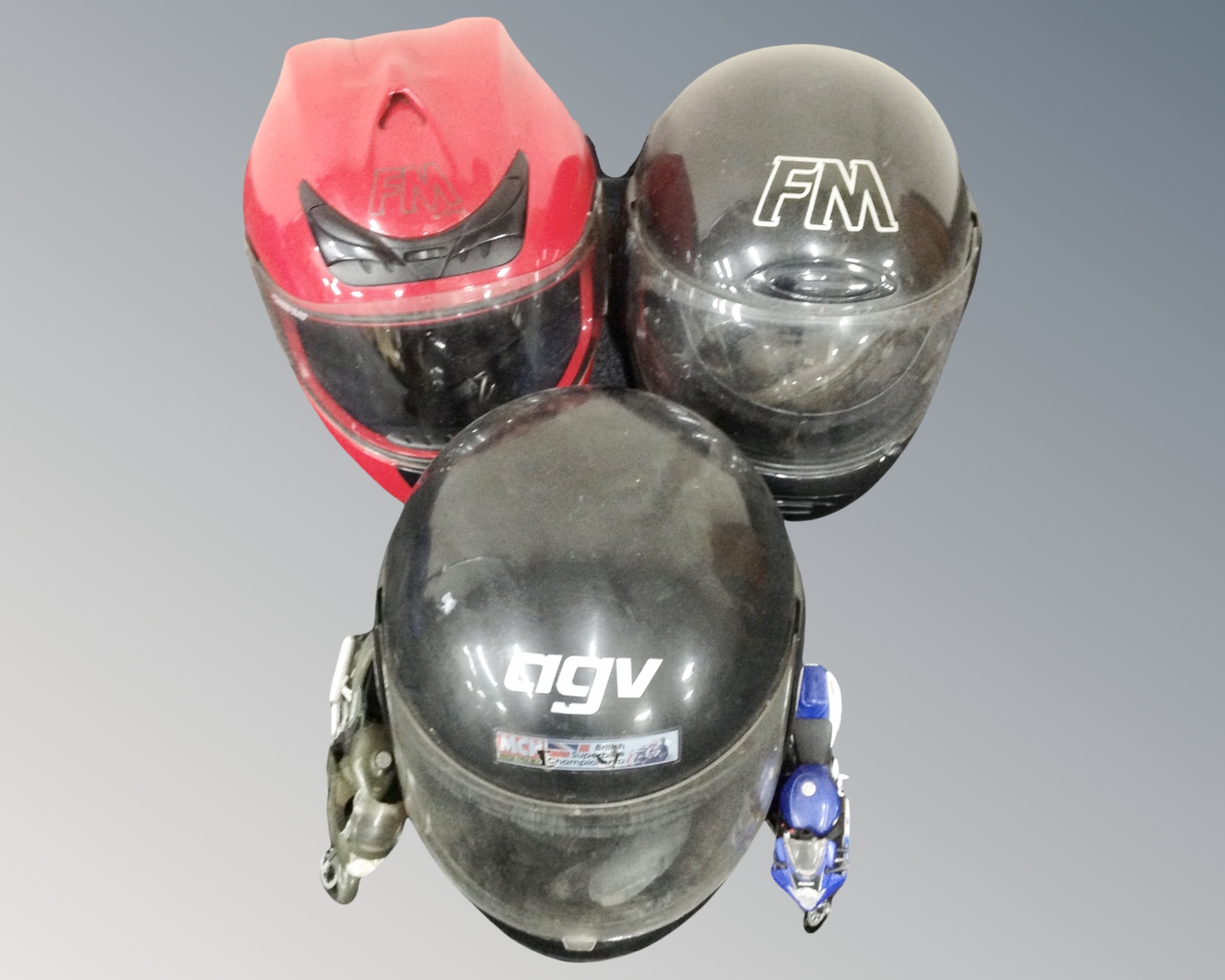 Three motorcycle helmets together with two motorcycle toys