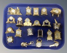 A tray of miniature metal cased desk clocks