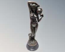 A bronze figure of a nude female carrying an urn, on marble socle,