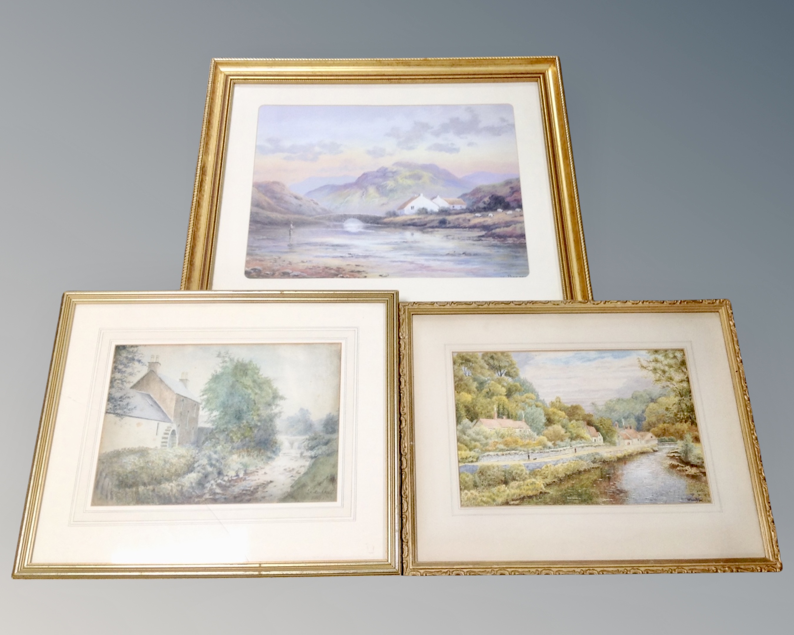 A W Wilson watercolour depicting figures by a river with dwellings beyond in gilt frame together