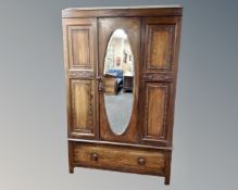 A three piece Edwardian oak bedroom suite comprising mirror door wardrobe,