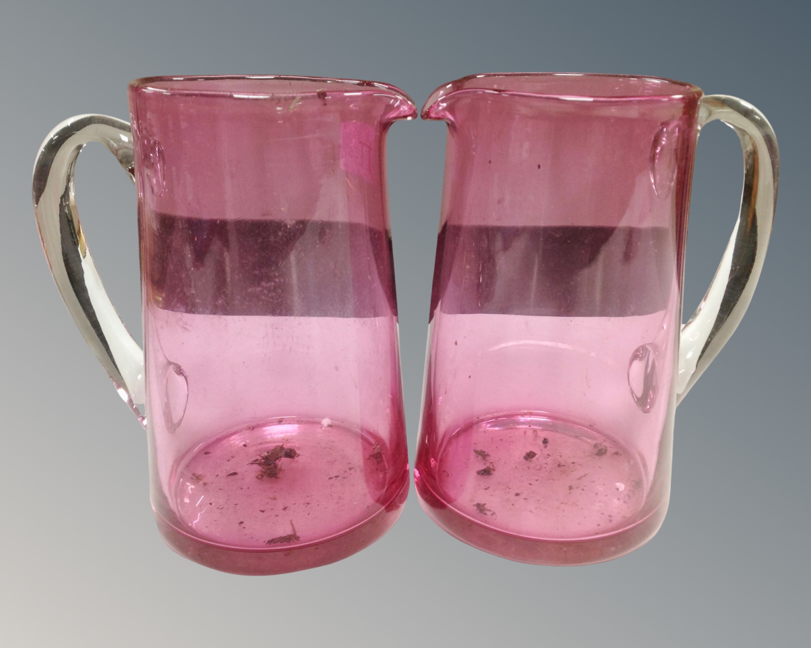 Two antique cranberry glass jugs together with a pair of lidded cranberry glass comports