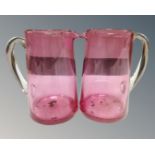Two antique cranberry glass jugs together with a pair of lidded cranberry glass comports