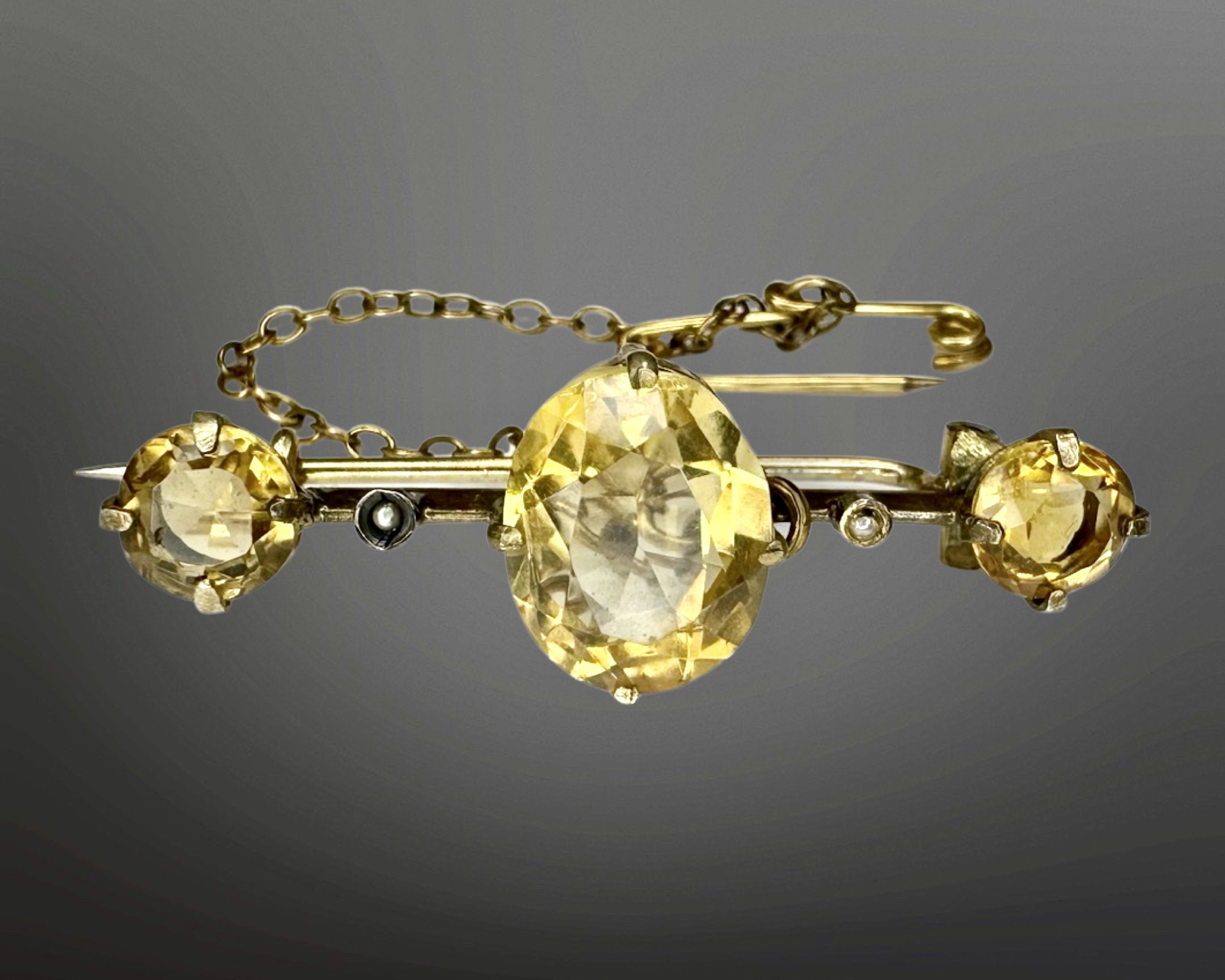 A Victorian yellow metal citrine and seed pearl bar brooch with safety chain, width 37mm.
