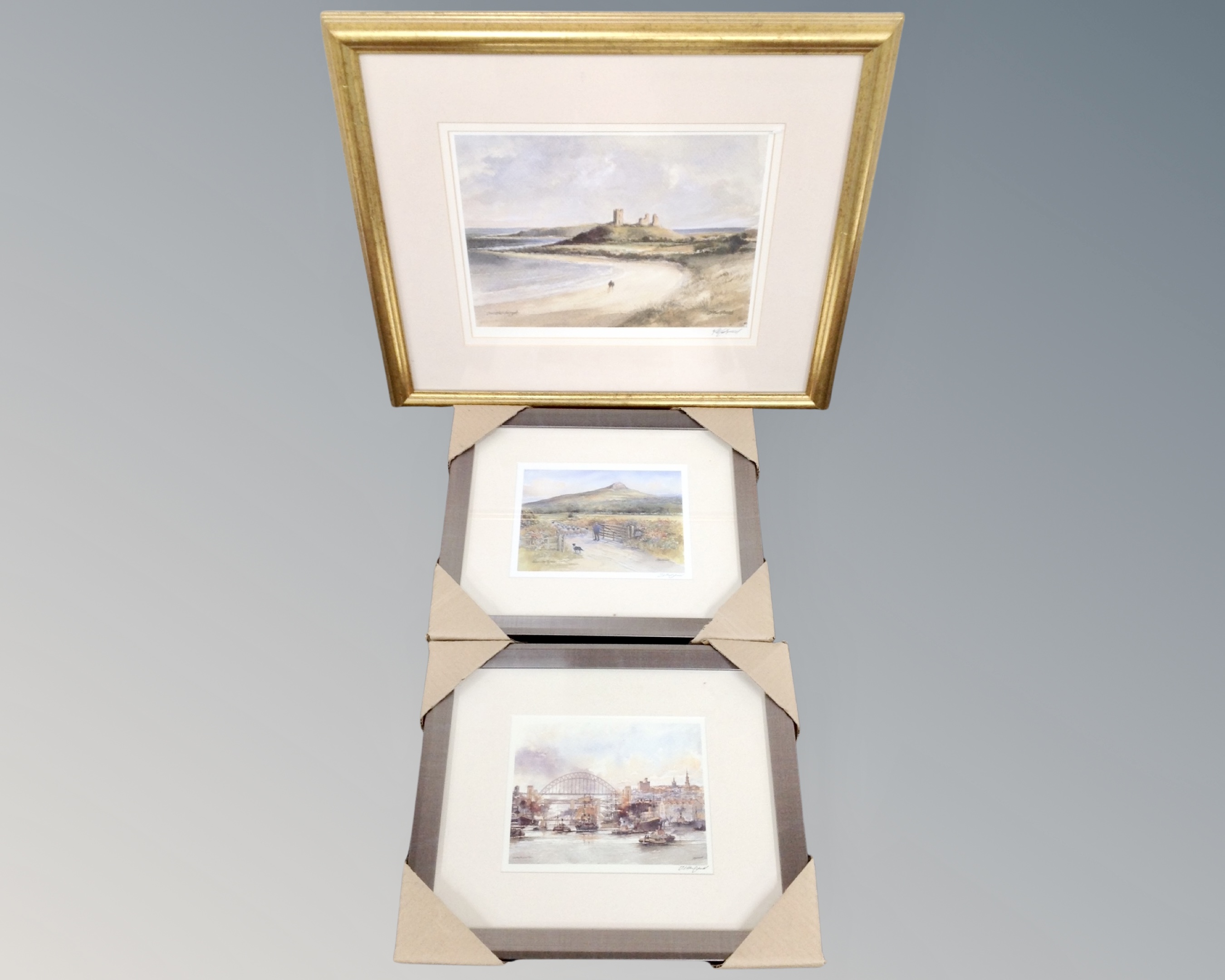 Three signed prints after Tom Macdonald depicting Dunstanburgh, Newcastle and Roseberry,