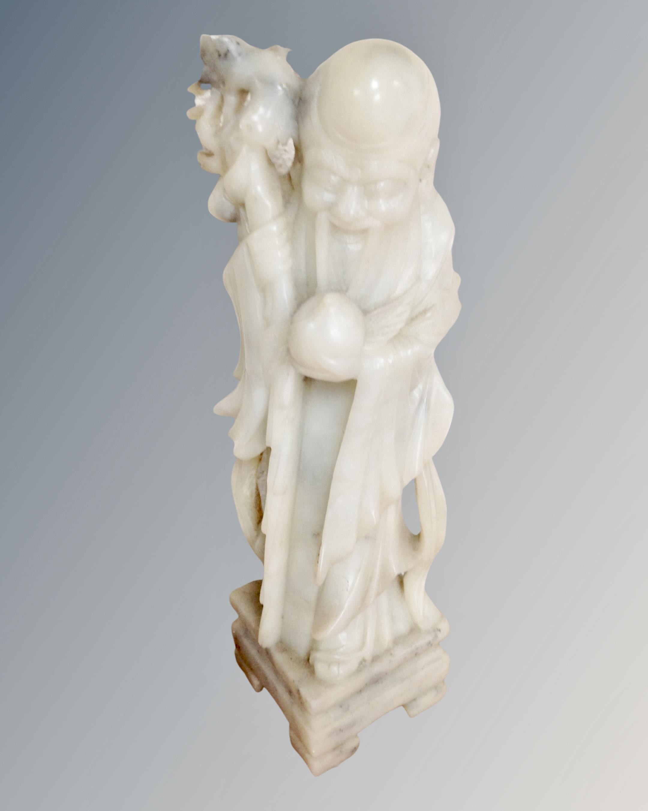 A carved Chinese hardstone figure depicting a man holding a staff.