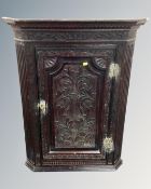 An early 19th century carved oak hanging corner cabinet