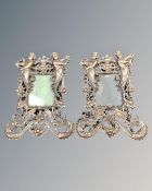 A pair of ornate photograph frames on easel stands.