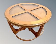 A circular teak G-plan coffee table with four inset glass panels fitted with four tables