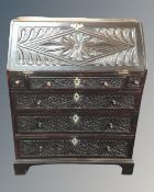 An early 19th century carved oak bureau fitted with six drawers