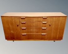 A mid century teak double door sideboard fitted with central drawers on castors