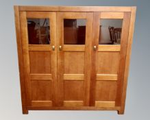 A pair of contemporary stained pine triple door cupboards