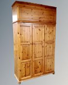 A contemporary pine triple door hanging wardrobe with top box