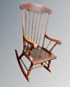 A stained beech wood spindle backed rocking chair