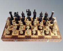 A chessboard with painted metal chess pieces.