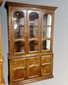 An American Colonial style triple door display cabinet fitted with cupboards