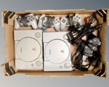 Two Sony PlayStation consoles with controllers and leads.