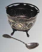 A silver swing handled bowl on raised feet, Sheffield 1876 hallmarks, together with a silver spoon.