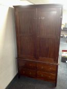 A contemporary mahogany double door hanging wardrobe fitted with four drawers beneath,