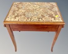 An Edwardian mahogany storage piano stool on raised legs.