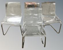 A set of four IKEA Tobias clear perspex dining chairs on metal legs.