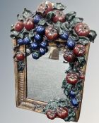 A decorative gilt framed mirror decorated with fruit.