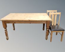 A pine farmhouse kitchen table together with a pair of contemporary leather seated dining chairs.