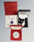 A silver shell cameo pendant on silver chain together with a purple glass pendant on silver chain,