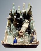 A box containing antique glass and ceramic bottles including brewery and chemist examples.