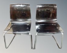 A pair of IKEA Tobias dark clear perspex dining chairs on metal legs.