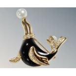 A Christian Dior yellow metal, enamel and white stone set seal brooch balancing a pearl on nose.