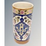 An early 20th century cylindrical pottery vase decorated with flowers.