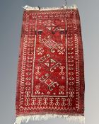 An Afghan rug on red ground, 75cm by 130cm.